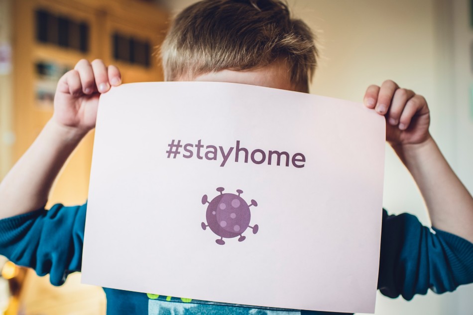 Bambino con in mano cartello che dice "Stay home" 